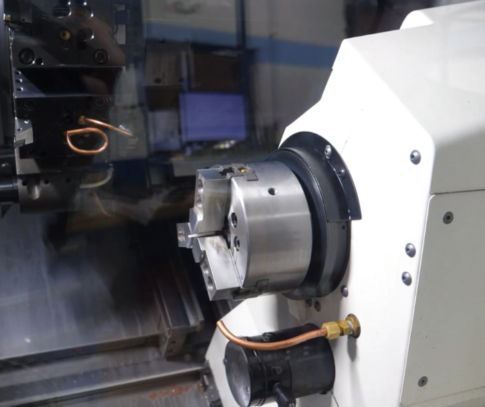 The image captures a segment of a CNC machine in operation, with a clear view of the chuck and the turret