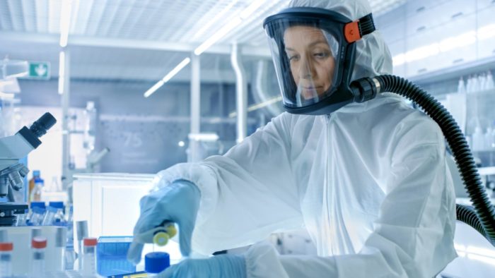 A worker in a full body hazmat suit working in a lab