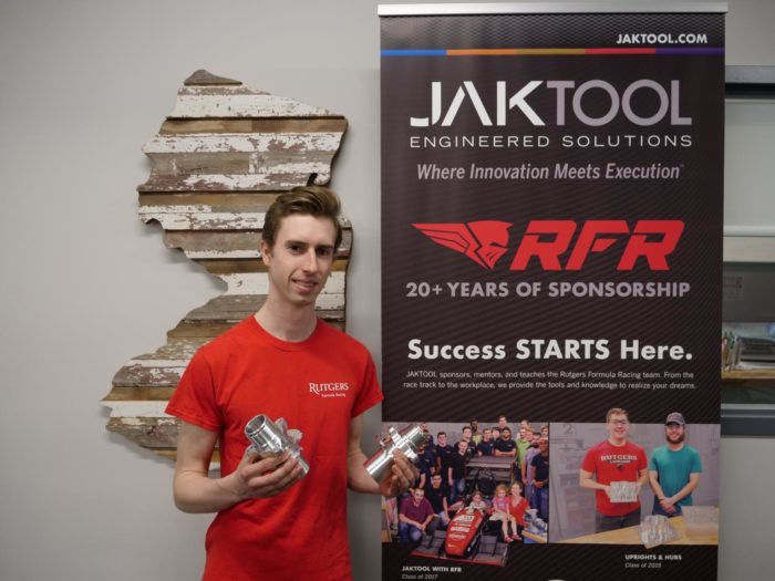 Employee posing with a prototype in front of a Jaktool banner reading "success starts here"