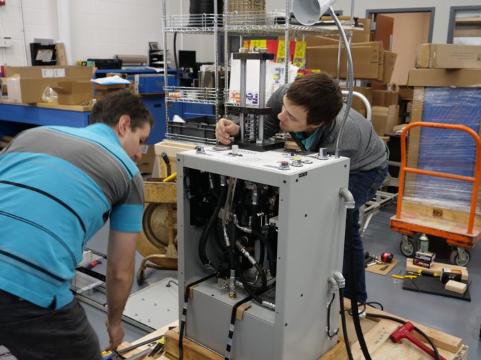 Two employees examining a machine as they work